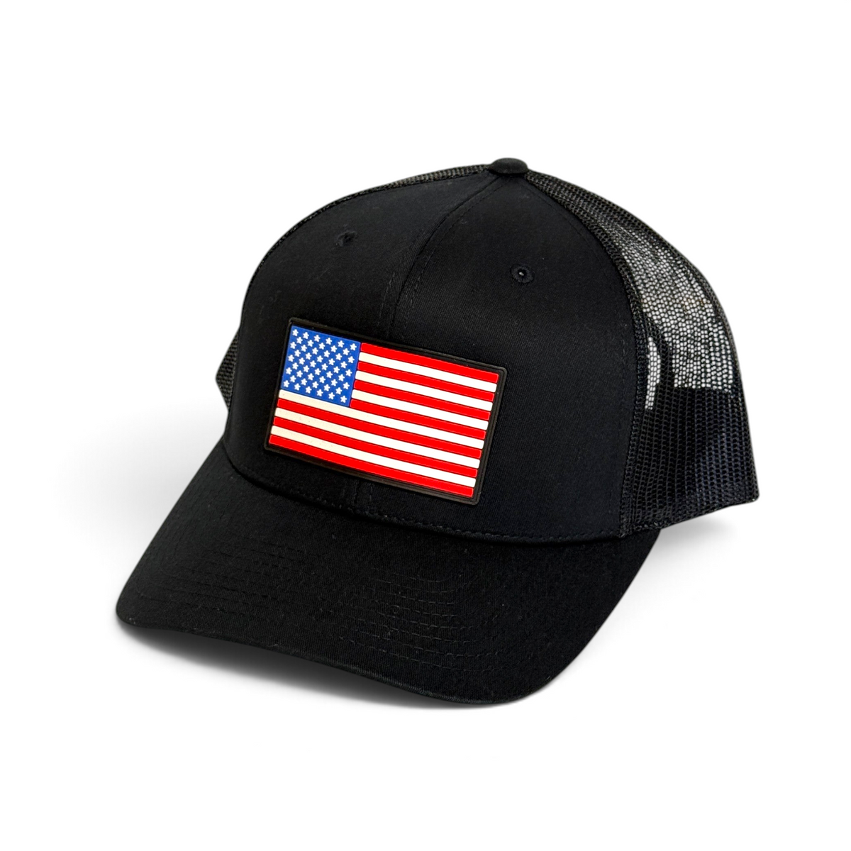 Crafted Merch black trucker hat featuring a rectangular American flag PVC patch and breathable mesh back panel.