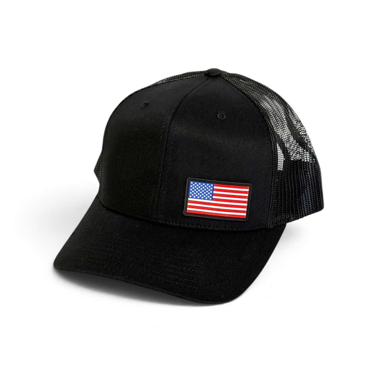Crafted Merch black trucker hat featuring a full-color American flag PVC patch and breathable mesh back panel.