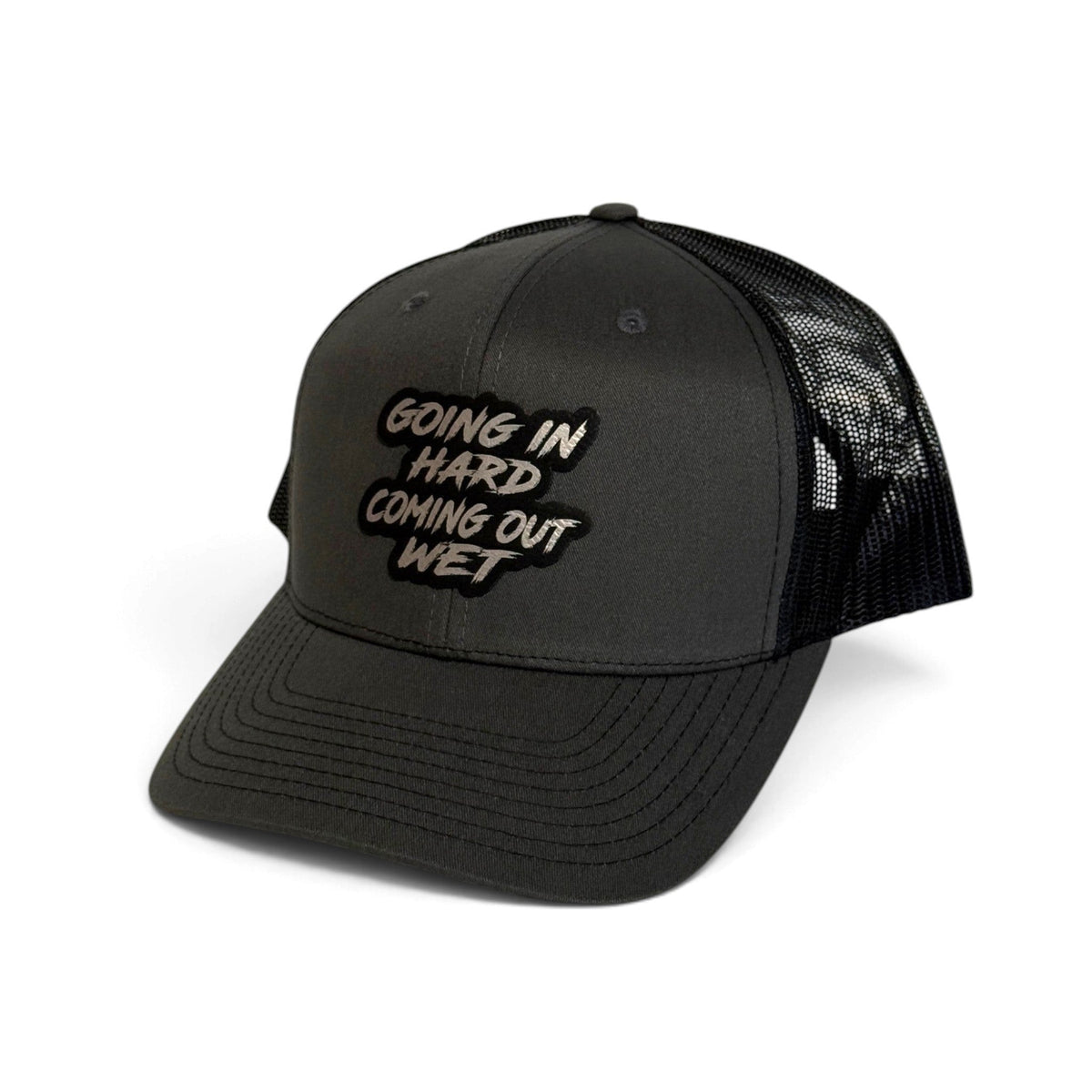 Crafted Merch black trucker hat with a patch featuring the text Going In Hard Coming Out Wet on a white background