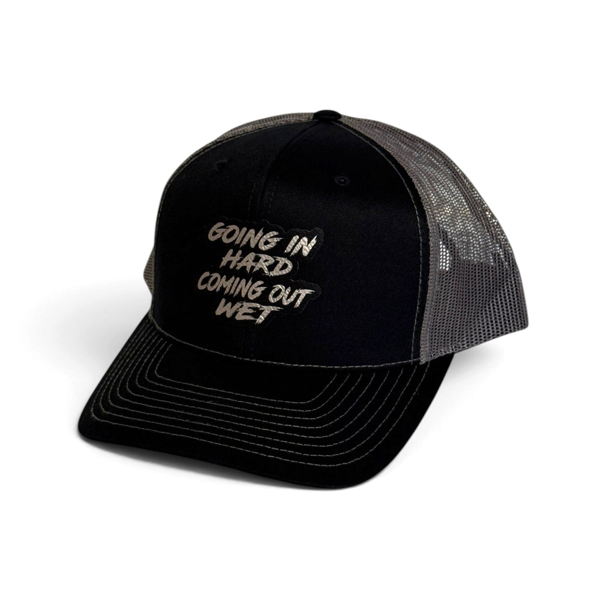 Crafted Merch black trucker hat with grey mesh back and embroidered Going In Hard Coming Out Wet patch on front