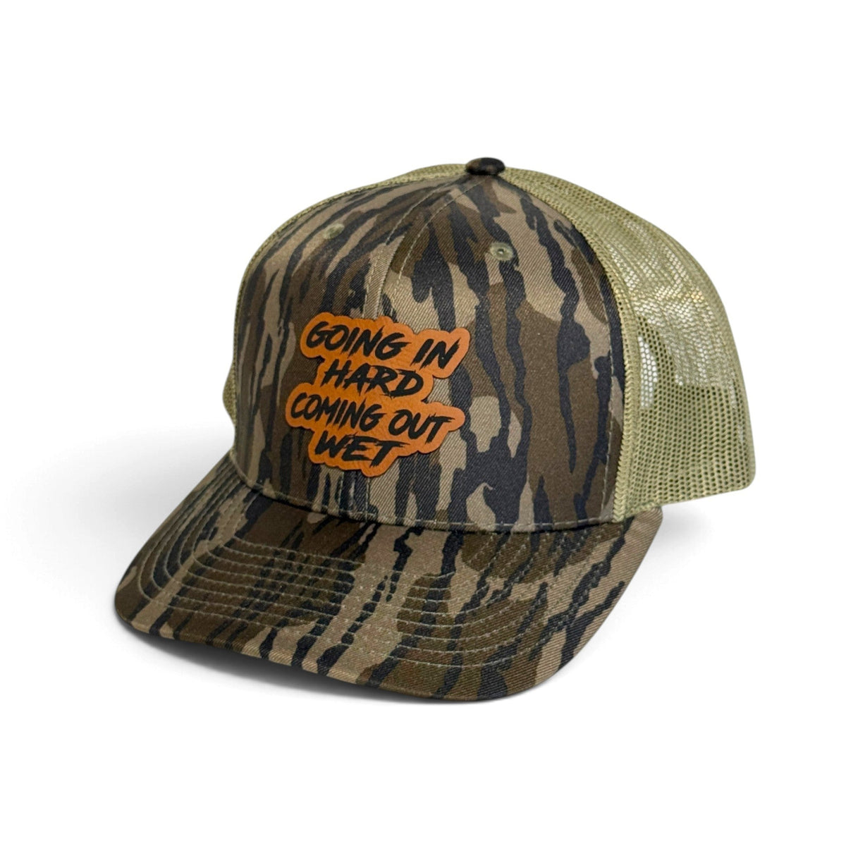 Crafted Merch trucker hat with camo print, olive mesh back, and an orange patch reading Going In Hard Coming Out Wet.