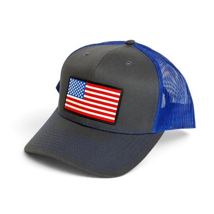 Crafted Merch trucker hat with a grey front panel, blue mesh back, and a full-color American flag PVC patch.